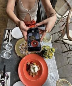 a woman sitting at a table in front of an orange plate with food on it