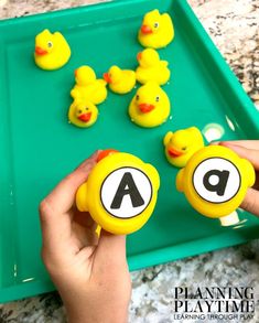 a child is playing with rubber ducks on a playtime tray that includes letters and numbers