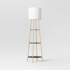 a tall wooden floor lamp with a white shade on it's top and black base