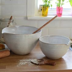 two white bowls sitting on top of a wooden counter