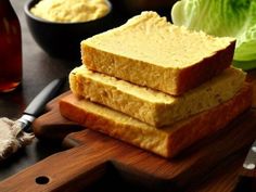 three pieces of bread sitting on top of a cutting board next to lettuce