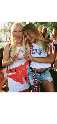 two young women standing next to each other in front of a group of people with their arms around one another