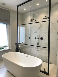 a large white bathtub sitting next to a window in a bathroom with marble flooring