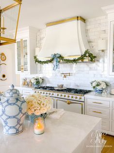 a kitchen with white cabinets and gold trimming on the hood above the stove is decorated for christmas