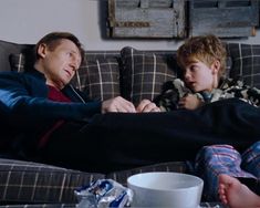 a man sitting on top of a couch next to a little boy