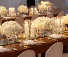 the table is set with white flowers and candles