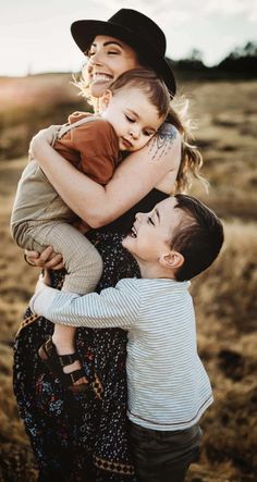 three children hugging each other in the middle of a field