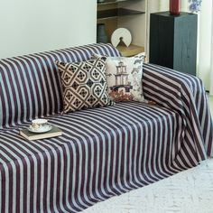 a striped couch with pillows on it in front of a book shelf and bookshelf