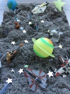 an assortment of toys are in a plastic container on the ground with stars around them