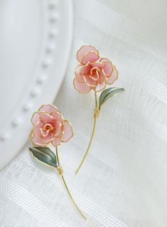 two pink flowers are sitting on a white surface