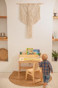 a little boy standing in front of a wooden desk