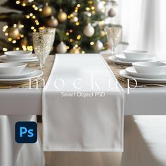 a table with white plates and silverware on it, next to a christmas tree