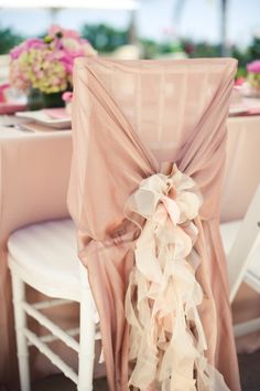 the back of a chair covered in pink chiffon with a flower on it