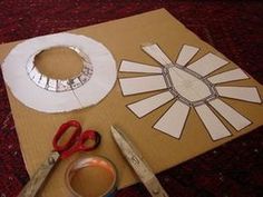 paper plates and scissors are sitting on top of a cardboard box that is cut out to look like a sun