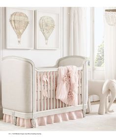 a white crib with pink ruffled bedding in a nursery