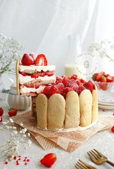 there is a cake with strawberries on the top and other desserts in the background