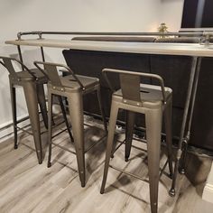 three metal bar stools sitting next to each other in front of a counter top