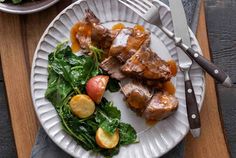 a white plate topped with meat and veggies next to a bowl of salad