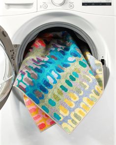 a multicolored towel sitting on top of a dryer next to a washer