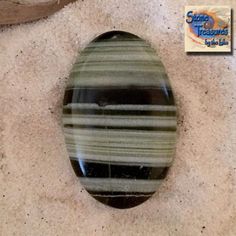 a green and black striped glass cabochon sitting on top of a white carpet