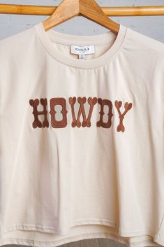 Update your casual style with our playful yet versatile Howdy Tee. Featuring bold brown stitching and "Howdy" lettering across the front, this shirt adds a touch of fun and personality to any outfit. The soft, lightweight material ensures a comfortable and breathable fit with just the right amount of stretch. Pair it with denim or a skirt for a concert friendly look. Fits true to size. Crop style in cream. 95% Cotton, 5% Spandex Brown Short Sleeve Tops With Letter Print, Brown Relaxed Fit Tops With Text Print, Casual Brown Shirt With Letter Print, Brown Text Print T-shirt For Summer, Brown Graphic Tee With Text Print, Brown Crew Neck Graphic Tee, Brown Crew Neck Graphic Tee Shirt, Brown Graphic Tee With Letter Print, Brown Crew Neck Top With Letter Print