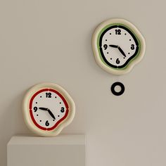 two clocks are on the wall and one is red, green and white with black numbers