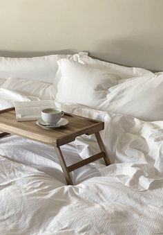 an open book and cup on a bed with white sheets