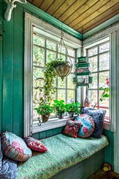 a window seat with pillows and plants on it