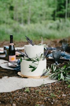 a white wedding cake sitting on top of a wooden table next to bottles and glasses