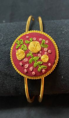 Hand embroidered golden roses. The embroidered piece is placed in a gold cuffed bracelet. The gold bracelet metal can be bent in or out to fit any sized wrist. Elegant Embroidered Bracelets As Gift, Elegant Embroidered Bracelets As A Gift, Gold Embroidered Bracelets For Wedding, Adjustable Embroidered Bangle Bracelet, Gold Embroidered Bangle Bracelet, Gold Jewelry With Floral Embroidery For Gift, Embroidered Christmas Ornaments, Golden Roses, Embroidered Bracelet