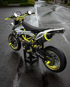 a yellow and black motorcycle parked on top of a metal stand in the middle of a street