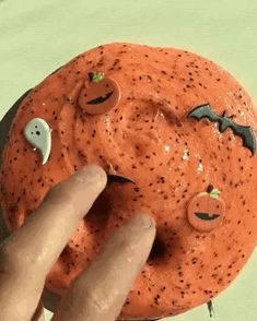 a hand holding a doughnut with spooky eyes and bats painted on it