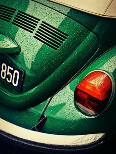 the back end of a green car with rain drops on it