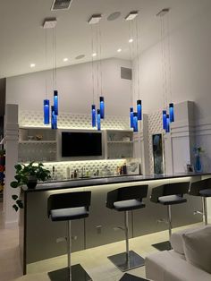 a kitchen island with stools and lights hanging from it's ceiling above the bar