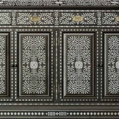 an ornate black and white cabinet with two doors on one side and three drawers on the other