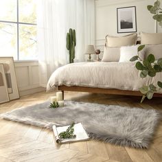 a bedroom with white walls and wood flooring is decorated in neutral tones, including an unkempt bed