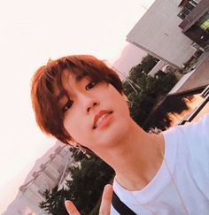 a young man making the peace sign with his hand while standing in front of a building