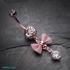 a pink bowknoted belly ring with a crystal ball on the end is shown