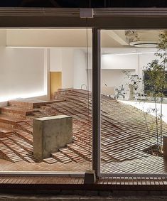 an empty room with wooden steps and plants in the center, as seen through large glass windows