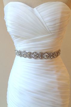 a strapless white wedding dress with beading on the waistline and bustle