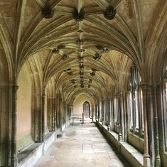 the inside of an old building with columns and arches on both sides, along with stone flooring