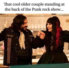 a man and woman standing next to each other in front of a counter with the caption that reads, that cool older couple standing at the back of the punk rock show