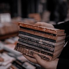 a person holding a stack of books in their hands