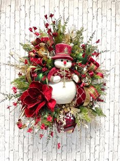 a christmas wreath with a snowman and poinsettis in it on a white wall