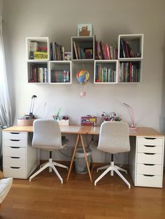 two chairs are sitting at a desk in front of bookshelves