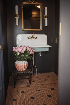 an iron farmhouse sink with pink flowers and candles in the background text reads vintage style cast iron farmhouse sink