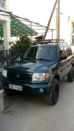 a green suv parked in front of a building