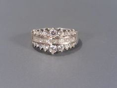 This beautiful sterling ring has two rows of clear cubic zirconia round stones in graduated size with a row of channel set square aka princess cut in the center. The ring is a size 8 and the front center vertically measures 11mm wide. Mark: 925 DQ CZ China and has been tested to ensure sterling silver purity. In wonderful condition, the stones are not damaged and have a nice sparkle, some light usage marks on the shank of the ring. Cz Ring, Victorian Jewelry, Channel Set, Multi Stone Ring, Art Deco Jewelry, Multi Stone, Princess Cut, Sterling Ring, Vintage Necklace