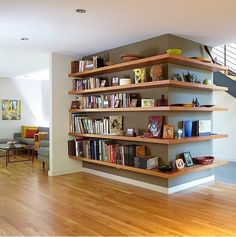 a living room filled with lots of furniture and bookshelves next to a stair case