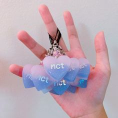 a hand holding four heart shaped keychains with words on them that say not to touch